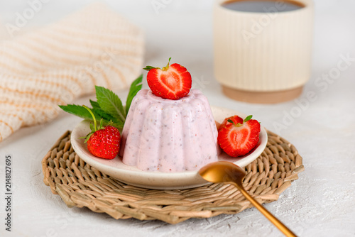 Natural homemade protein dessert with strawberries, chia seeds and creamy cottage cheese with cup of tea on a light table.