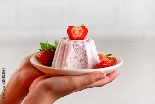 Natural homemade protein dessert with strawberries, chia seeds and creamy cottage cheese in a hands.