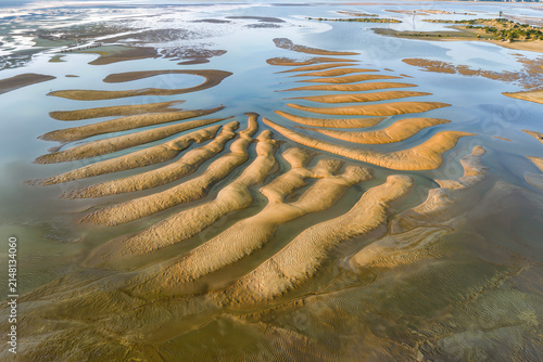 Aerial view of vast desert sand dunes rolling to the horizon with sharp crests and deep shadows at sunrise