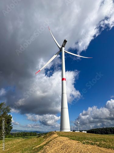 Obraz na płótnie Tall wind turbine with dramatic cloudy sky backdrop