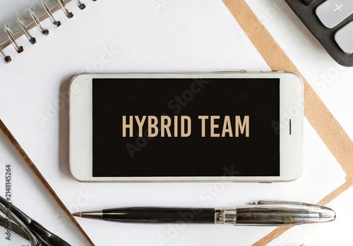 Mobile on desk with words Hybrid Team - Combination of in-office and remote work. Some members work from central office, while others work from home. Flexibility of remote jobs mixed with Face-to-face