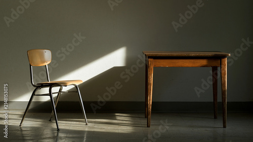 detention. Empty school chair with beam of cold daylight beside plain wall, discipline and silent reflection concept, lifestyle magazines.