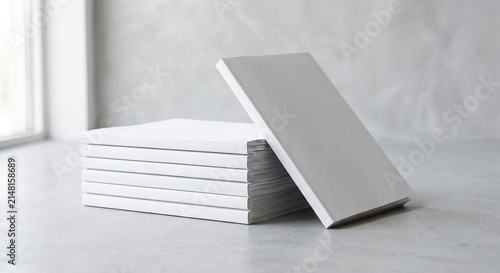 Minimalist stack and leaning blank white matte magazines mockup on a light gray background with soft shadows.