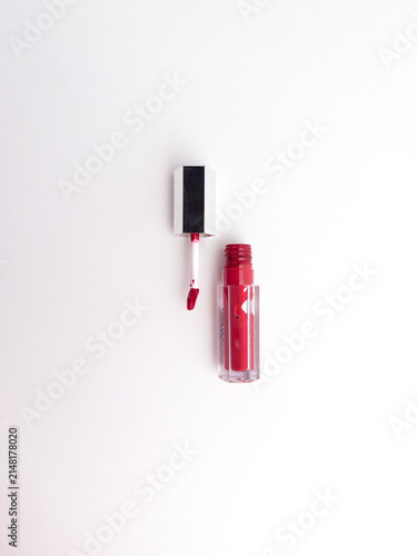 Red liquid lipstick and applicator wand flat lay isolated on a clean white background