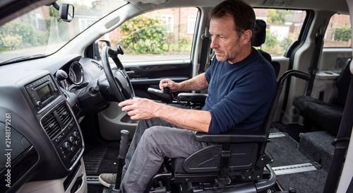 A man with a disability sits comfortably in the driver seat of a specially adapted van designed for wheelchairs.