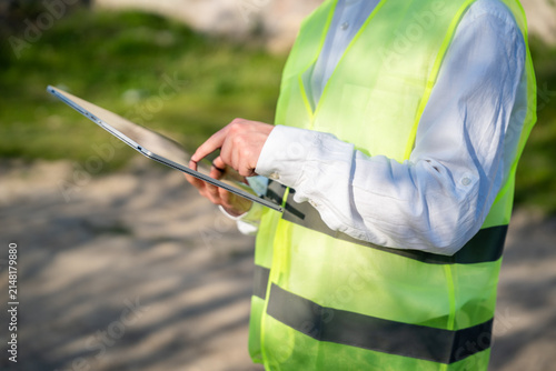 Engineer using tablet computer on construction site wearing safety vest. Digital workflow mobile construction documentation and engineering tools