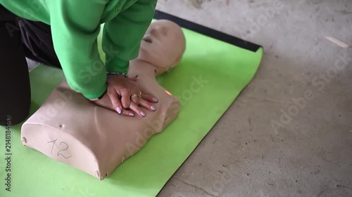 First aid instructor demonstrating cpr chest compressions on a medical training manikin during a lesson