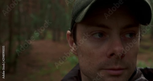 Close up portrait of man in cap walking through rainy forest