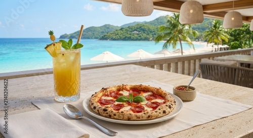 Wood-fired pepperoni pizza served with a refreshing tropical pineapple mocktail on an oceanfront restaurant terrace overlooking a turquoise tropical bay. Luxury beach dining, vacation lifestyle and go