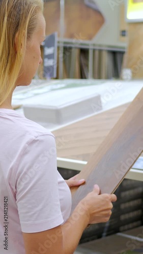 Woman Inspecting Laminate Flooring Sample in Home Improvement Store
