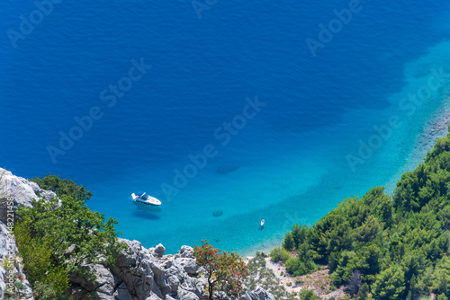 Turquoise Adriatic bay below Biokovo near Makarska, Dalmatia, Croatia, with boat and limestone cliffs.