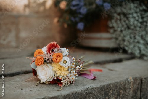 Bouquet de mariée coloré posé sur des marches en pierre avant la cérémonie