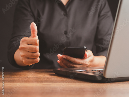 Person showing thumbs up while using smartphone