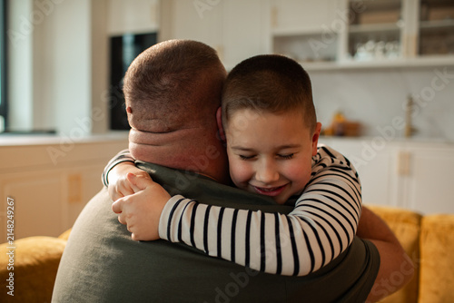 Loving father hugging happy son in kitchen