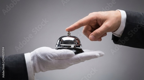 Hand pressing a hotel service bell. Concierge receiving a request for assistance.