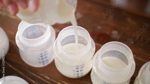 Fresh breast milk pouring into baby bottles, mother preparing infant formula for storage, healthy nutrition for newborn feeding