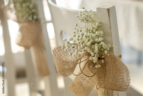 Wooden wedding chair with gypsophila paniculata flower arrangement and burlap ribbon decoration for sustainable event marketing campaigns