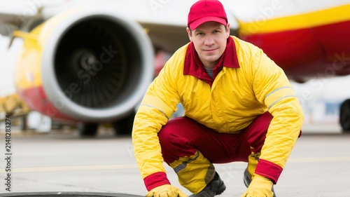 service worker in a colorful uniform sitting beside a large vehicle engine, symbolizing customer service, professional workforce, maintenance, transportation, industry, business operations