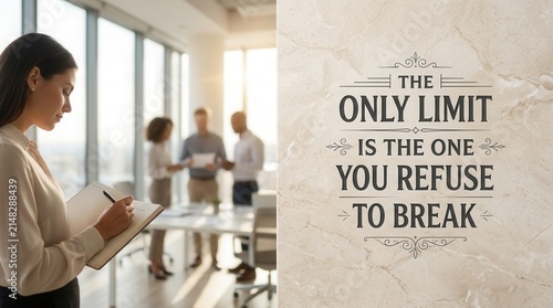 Professional young woman writing notes in modern office with team members in background and motivational quote on wall