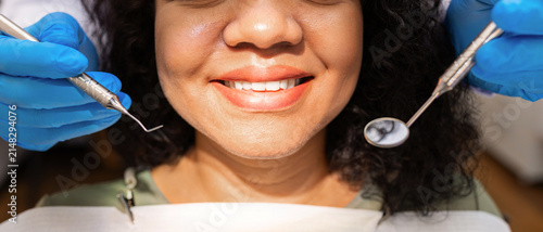 фотографія Closeup portrait of smiling female patient during dental examination with profes