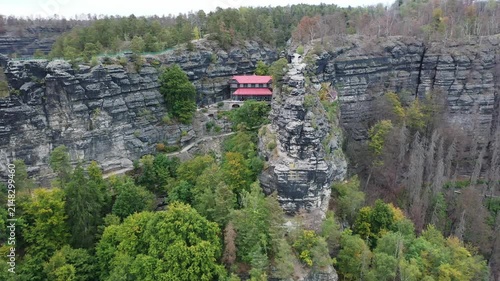 Aerial view of the historic Pravcicka brana stone archway nestled within the sandstone rock formations and lush forest of Hrensko, Ustecky kraj, Czechia.