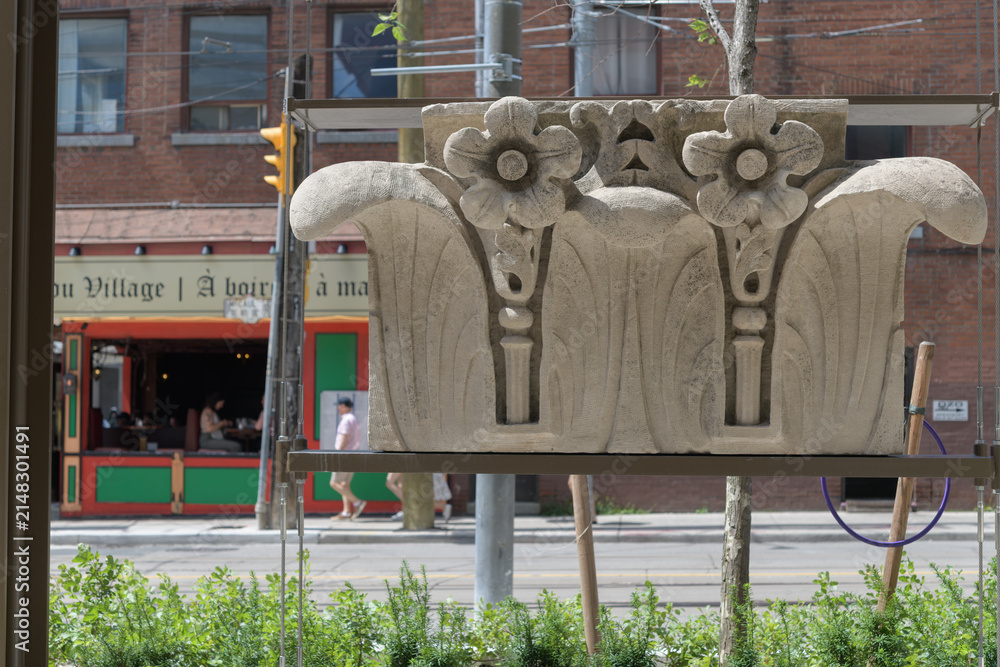 Fototapeta premium historic architectural carvings at Gallery Park at 129 McCaul St, Toronto (with defocused view of Village Idiot Pub)