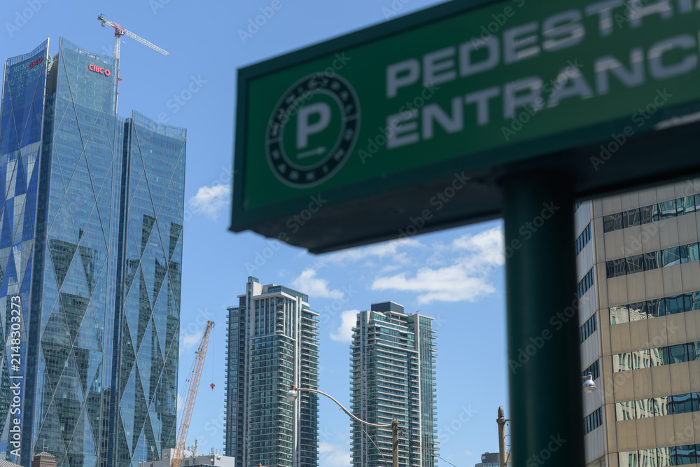 Fototapeta premium defocused Municipal Parking sign on a blue sky with view of CIBC Square and condominium complexes, Toronto