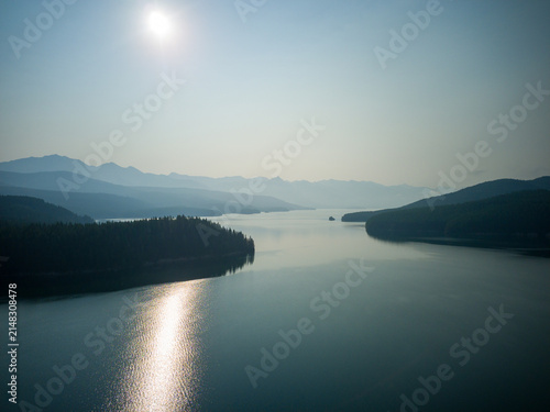 Obraz na plátně Serene lake reflects sun's glow across calm waters