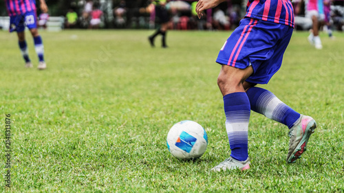 Canvas Print Football player dribbling the ball across grass field during competitive outdoor