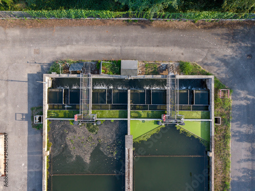 Aerial view of the water treatment facility featuring concrete basins, metal walkways, and flowing water surrounded by asphalt paths in Chivasso, Piedmont, Italy.