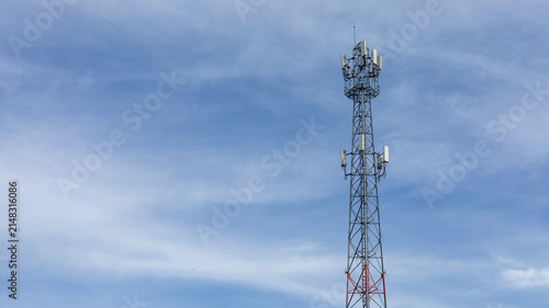 Obraz na plátně A cell tower rises high against a bright blue sky with scattered clouds