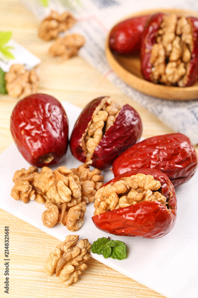 Fototapeta premium Xinjiang Jujube Dates Stuffed with Walnut Kernels - Healthy Traditional Chinese Snacks on Wooden Background