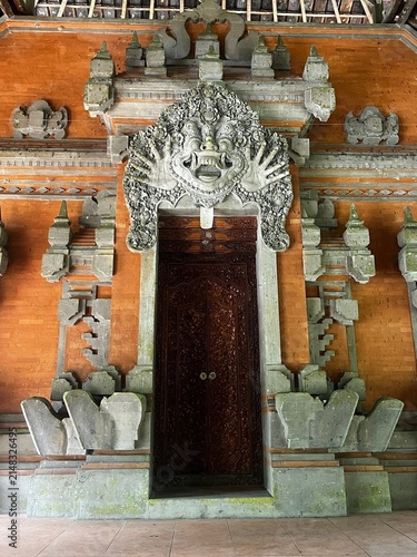 Konstfotografi Ancient Balinese architecture featuring intricately carved wooden door and spiritual stone mask, Ubud