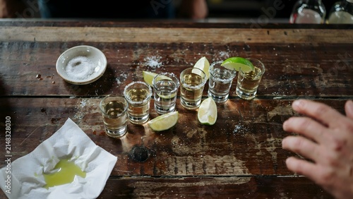 Shot of tequila glasses with lemon wedges and salt on rustic wooden table