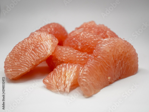 Studio composition of peeled red pomelo slices showing natural cell vesicles texture.