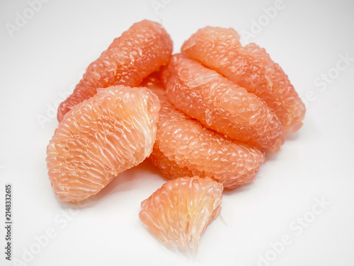 Freshly peeled pink pomelo fruit pieces ready to eat, isolated on a white background