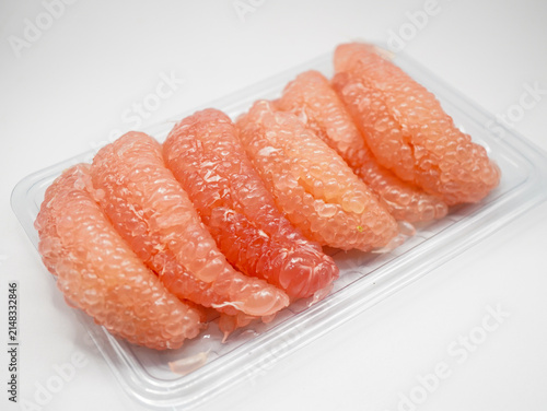 Close-up of fresh peeled pink pomelo citrus fruit segments isolated on a white background