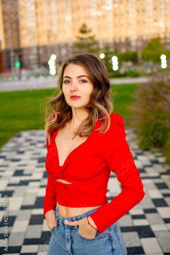 a beautiful young girl walking in the summer in a red sweater, a girl in the park in the summer, a portrait