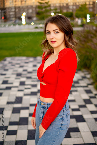 a beautiful young girl walking in the summer in a red sweater, a girl in the park in the summer, a portrait