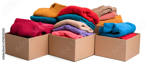 Cardboard boxes containing folded, brightly colored sweaters, set against a clear backdrop