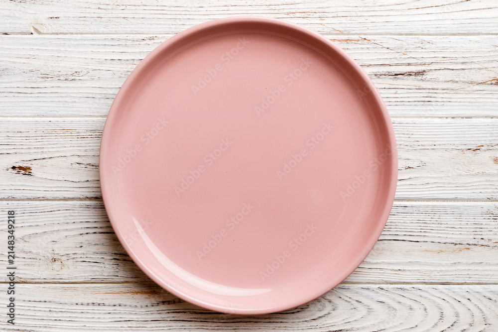 Obraz premium Top view of empty pink plate on wooden background. Empty space for your design