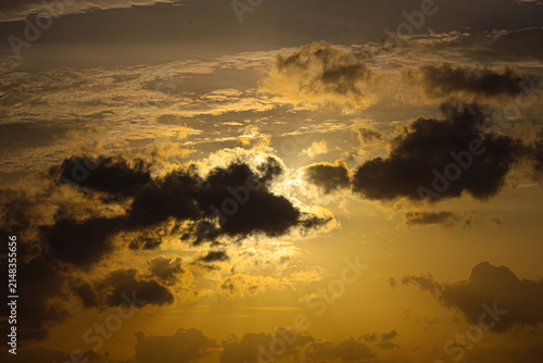 Quadro su tela Sunlight breaks through dark storm clouds during a dramatic golden hour sunset in the open sky