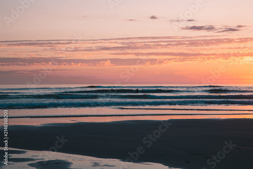 Peaceful Ocean Waves Rolling onto Sandy Shore at Pastel Pink Sunset