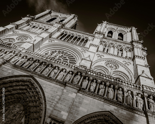 Dramatic low angle black and white view of the Gothic west facade, Gallery of Kings and towers of Notre-Dame Cathedral in Paris, France