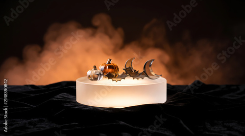 Glowing frosted glass cylinder podium with glass pumpkin and bats decorations in fog