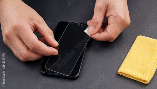 Black smartphone screen protector tab being peeled off by fingers