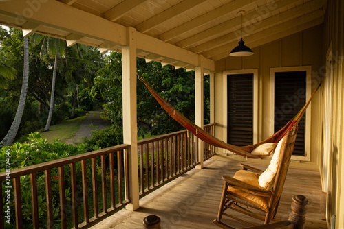Sunrise glow on lanai, porch in Hawaii with jungle outside and chairs and hammock on porch