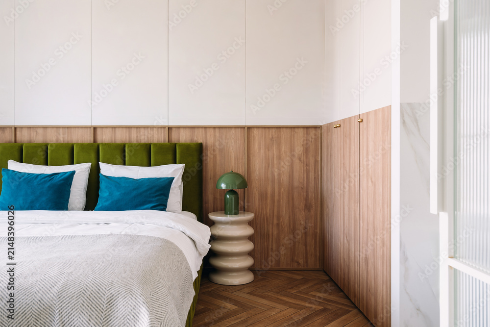Fototapeta premium Modern hotel bedroom with gree headboard on bed and lamp on side table