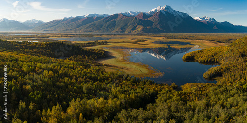 фотографія Alaskan snow-capped mountains in distance during fall with rising sun on the val