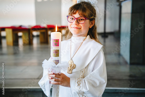 Canvastavla Child girl in traditional white first communion clothing holding a candle inside a Catholic church during a religious celebration